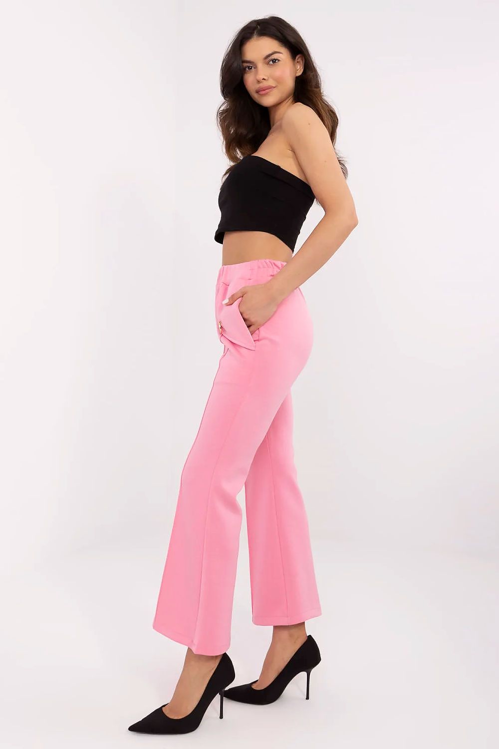 Sophisticated side view of Italy Moda high waist bell-shaped sweatpants in pink, highlighting the wide legs and side pockets, paired with a sleek black crop top and classy high heels.