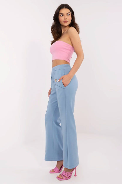 Side profile of a fashion-forward woman in Italy Moda high waist bell-shaped sweatpants in a serene blue hue, paired with pink heels, emphasising a chic casual look.