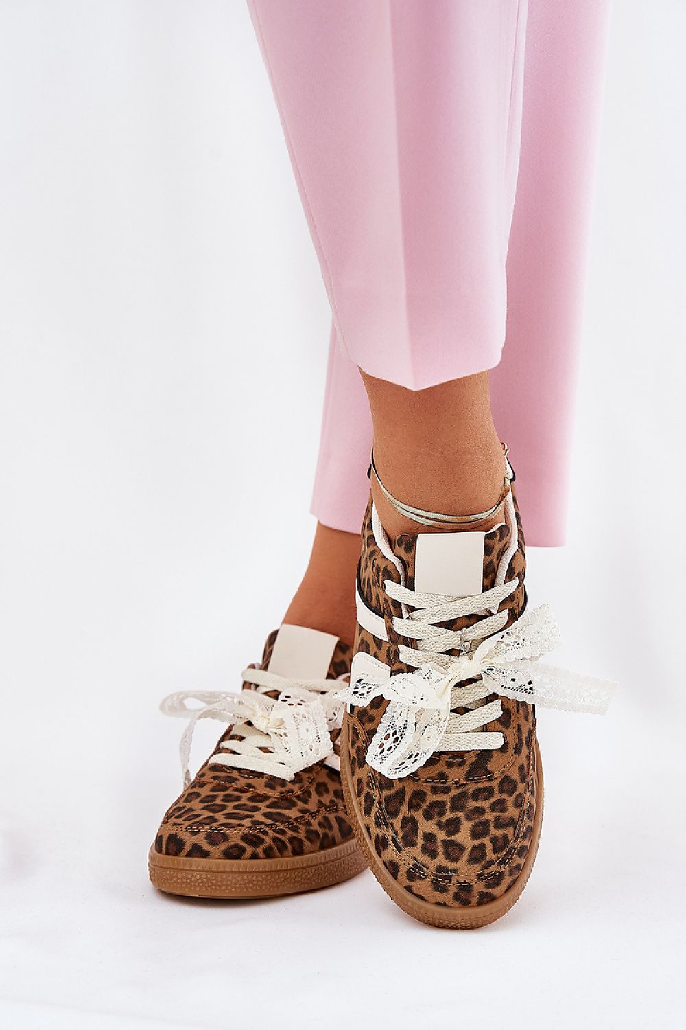 Fashion-forward women's leopard print sneakers with detachable lace detailing, complemented by fashionable pink trousers, from Step in Style.