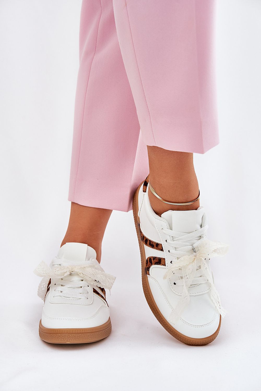 Close-up view of a woman wearing stylish eco leather sneakers with leopard print accents by Step in Style, paired with pink tailored trousers for a sophisticated outfit.