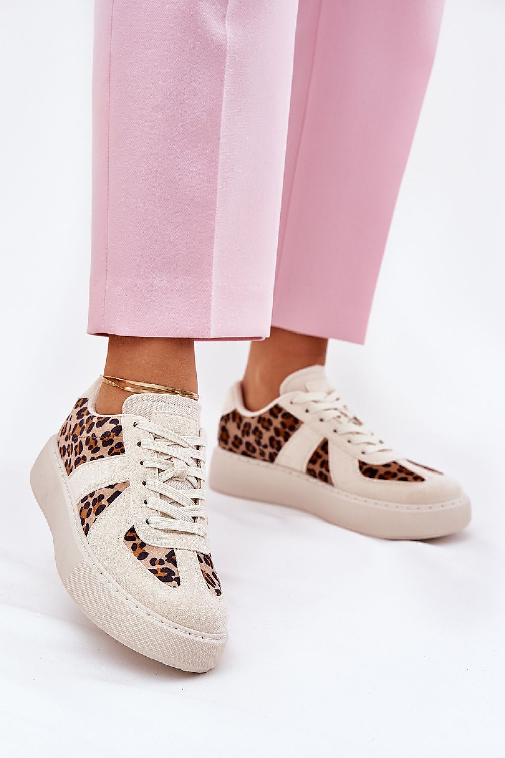 Elegant cream luxury women's sneakers with leopard print, designed by Step in Style, paired with pastel pink trousers.