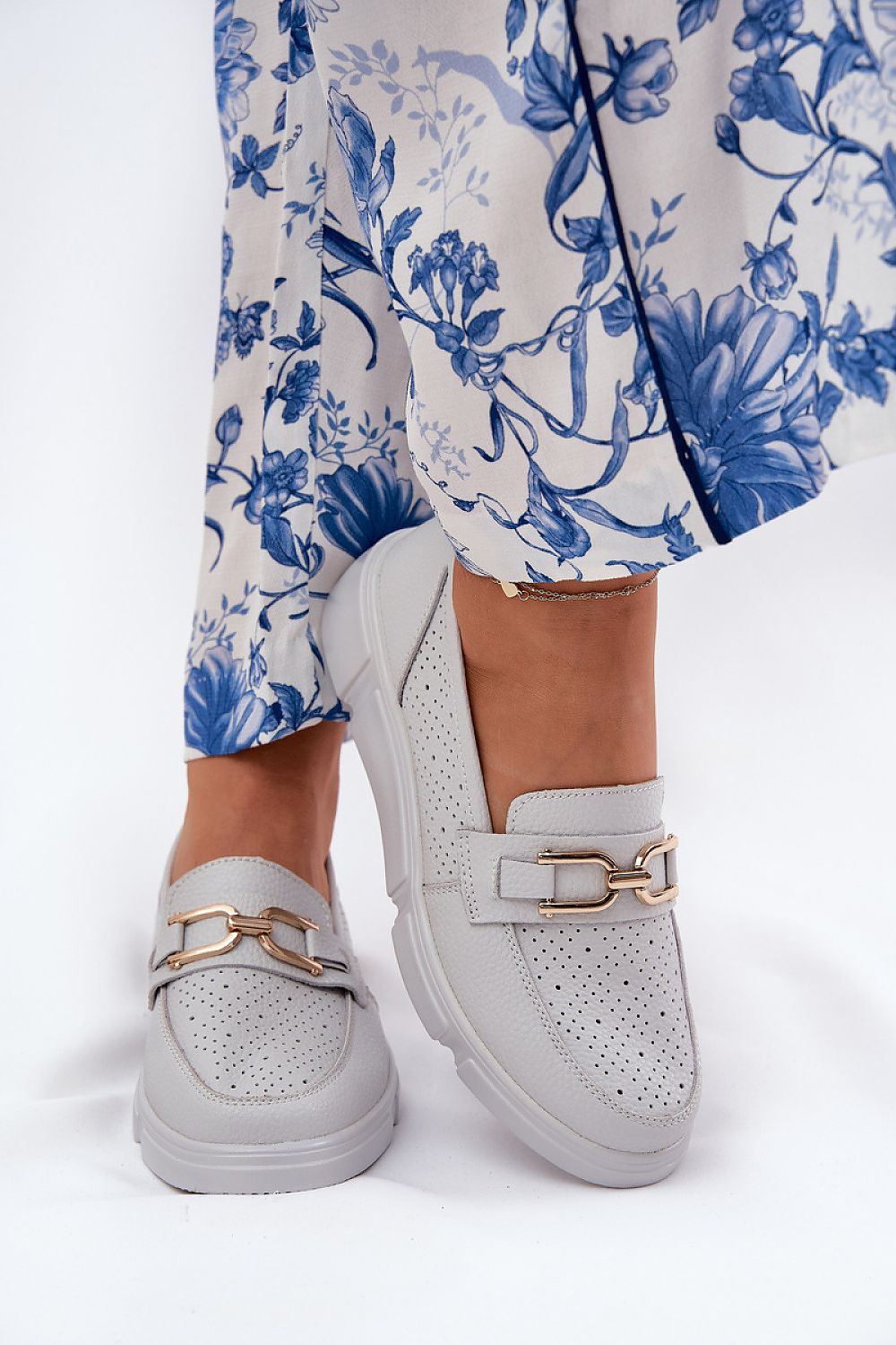 Close-up view of the natural leather upper of Step in Style women's moccasins, featuring a refined golden ornament.