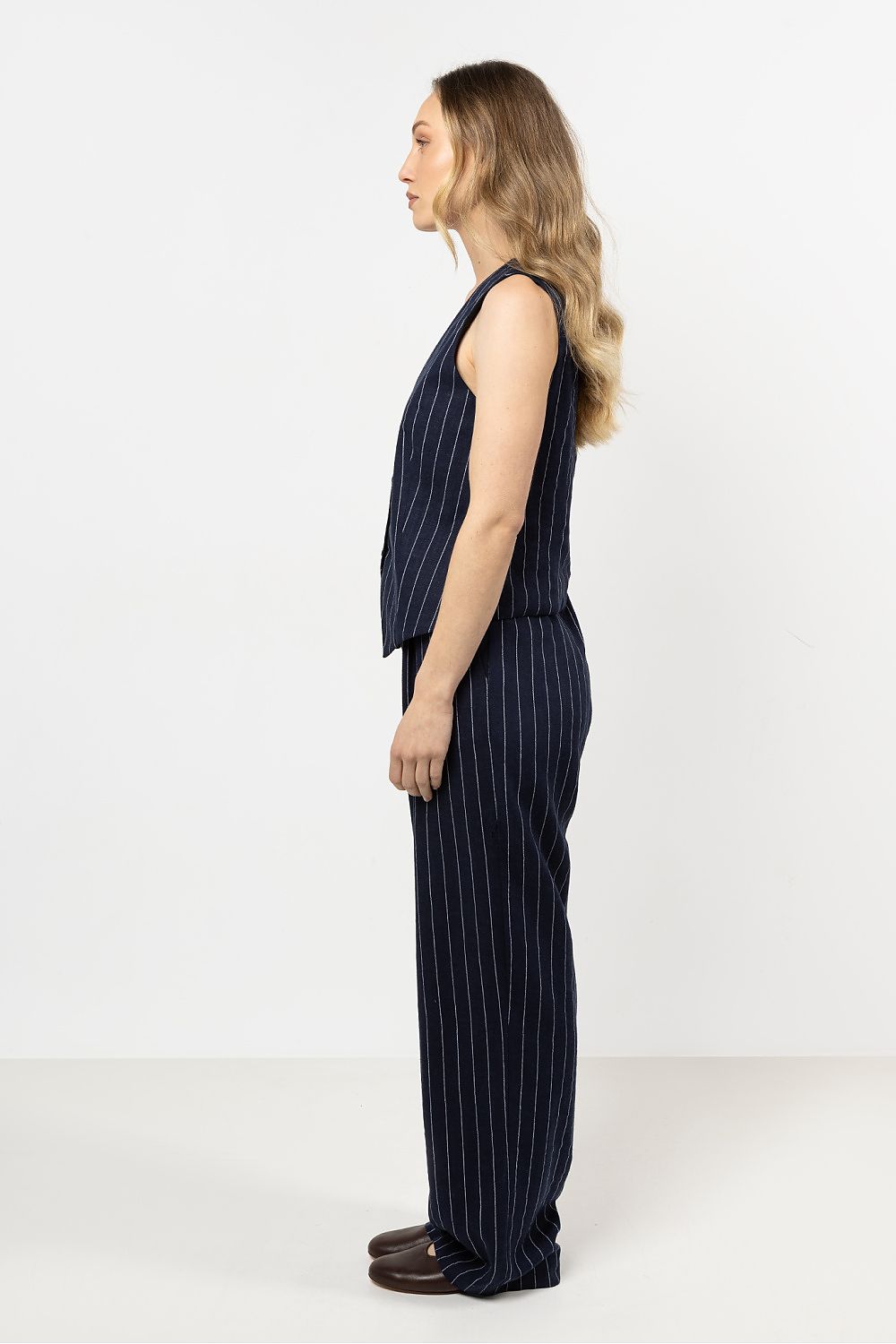 Model wearing awama's elegant linen trousers with wide legs and stripes, perfect for a chic summer look.