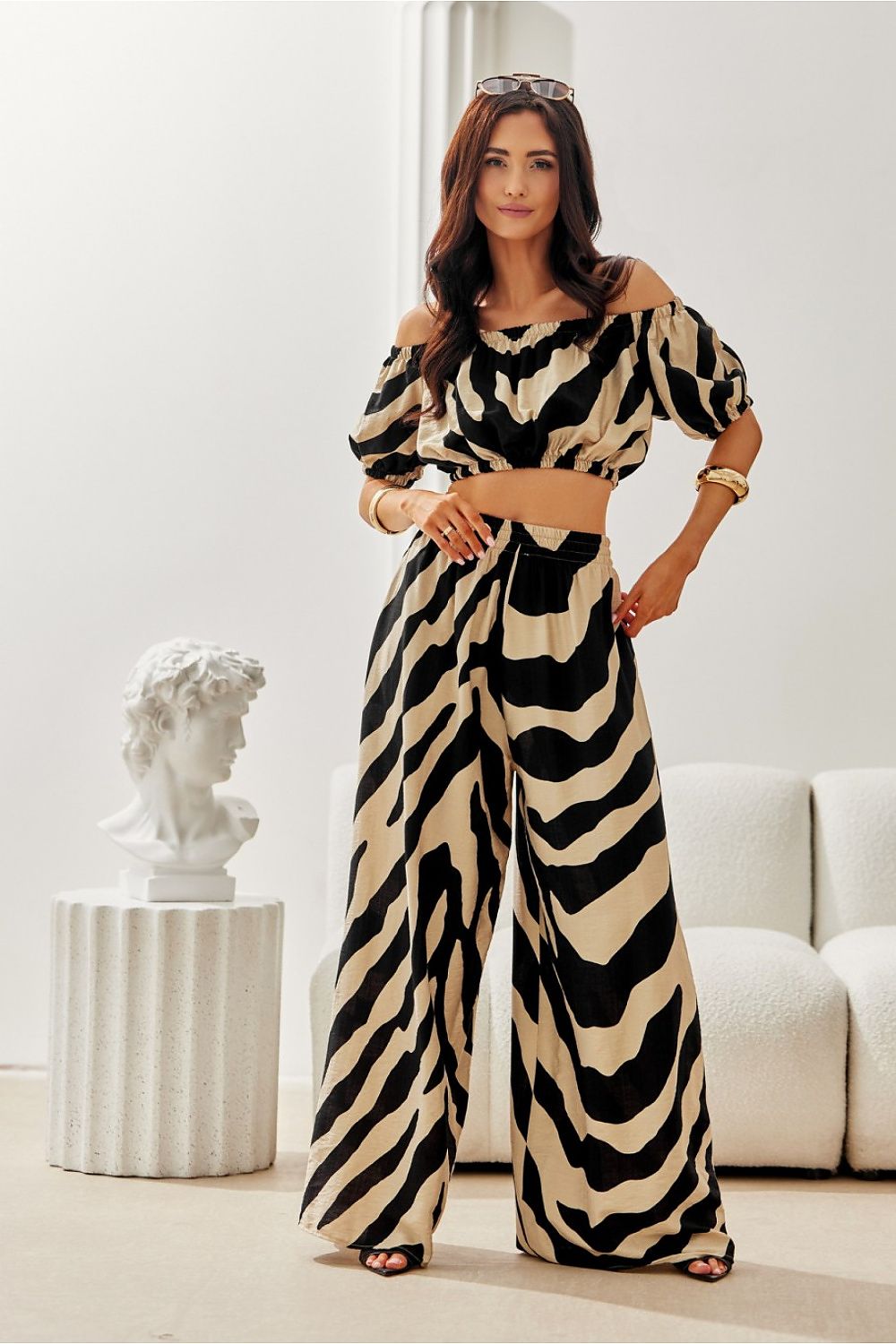 Model wearing Roco Fashion Noemi Summer Blouse at a beach, illustrating its romantic crop cut and flattering elastic waist, ideal for summer outings.