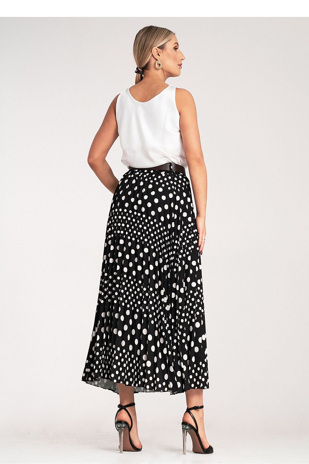 Close-up of Figl’s elegant pleated midi skirt featuring a delicate white polka dot pattern, designed to highlight the waist with its sophisticated high-waisted fit.