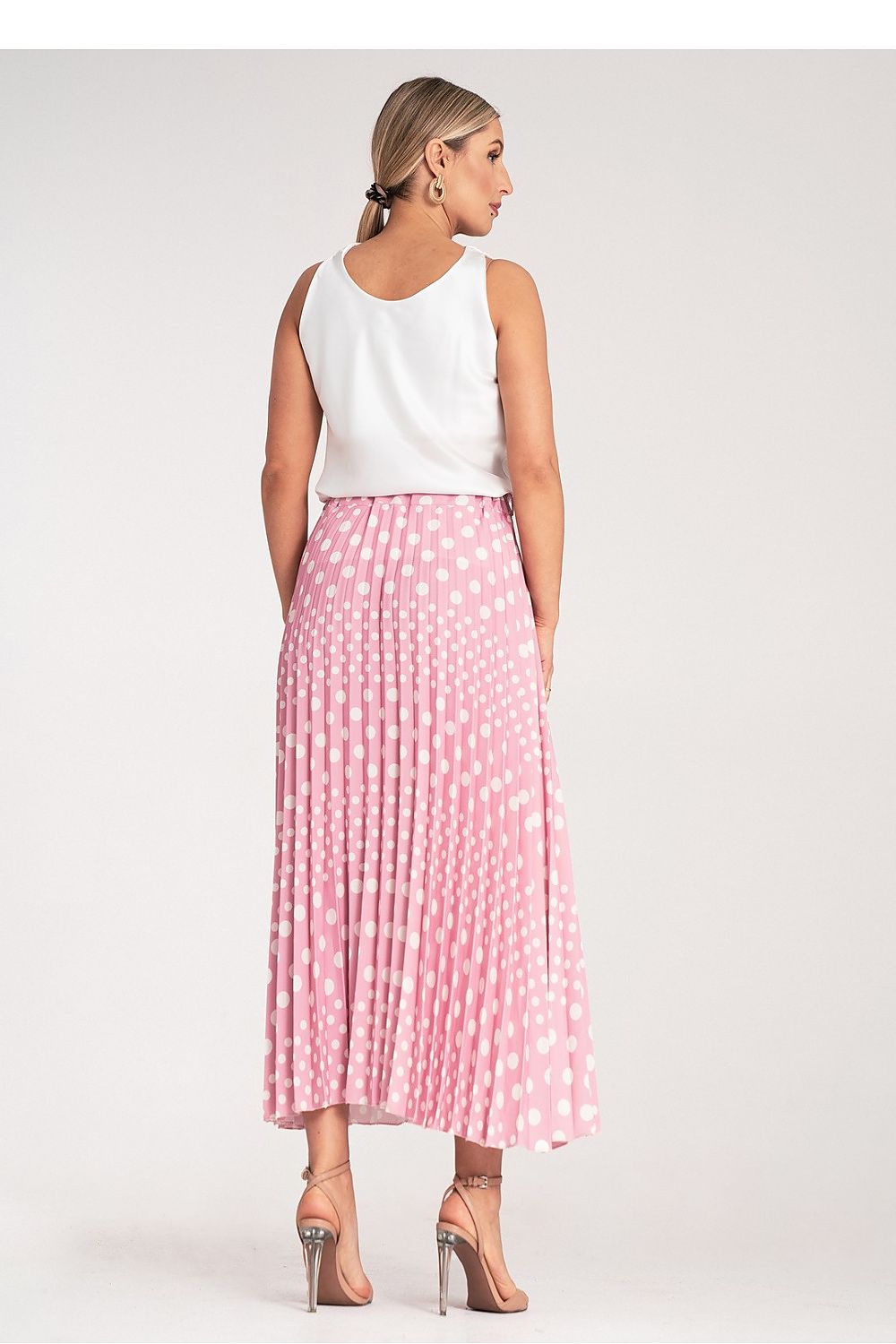 Model wearing the Figl high-waisted pleated midi skirt with white polka dots, demonstrating its stylish fit and versatility.