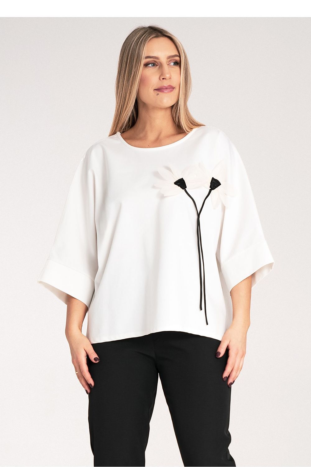 Close-up of Figl's luxury kimono blouse, highlighting the decorative flower on the chest and stylish round neckline.