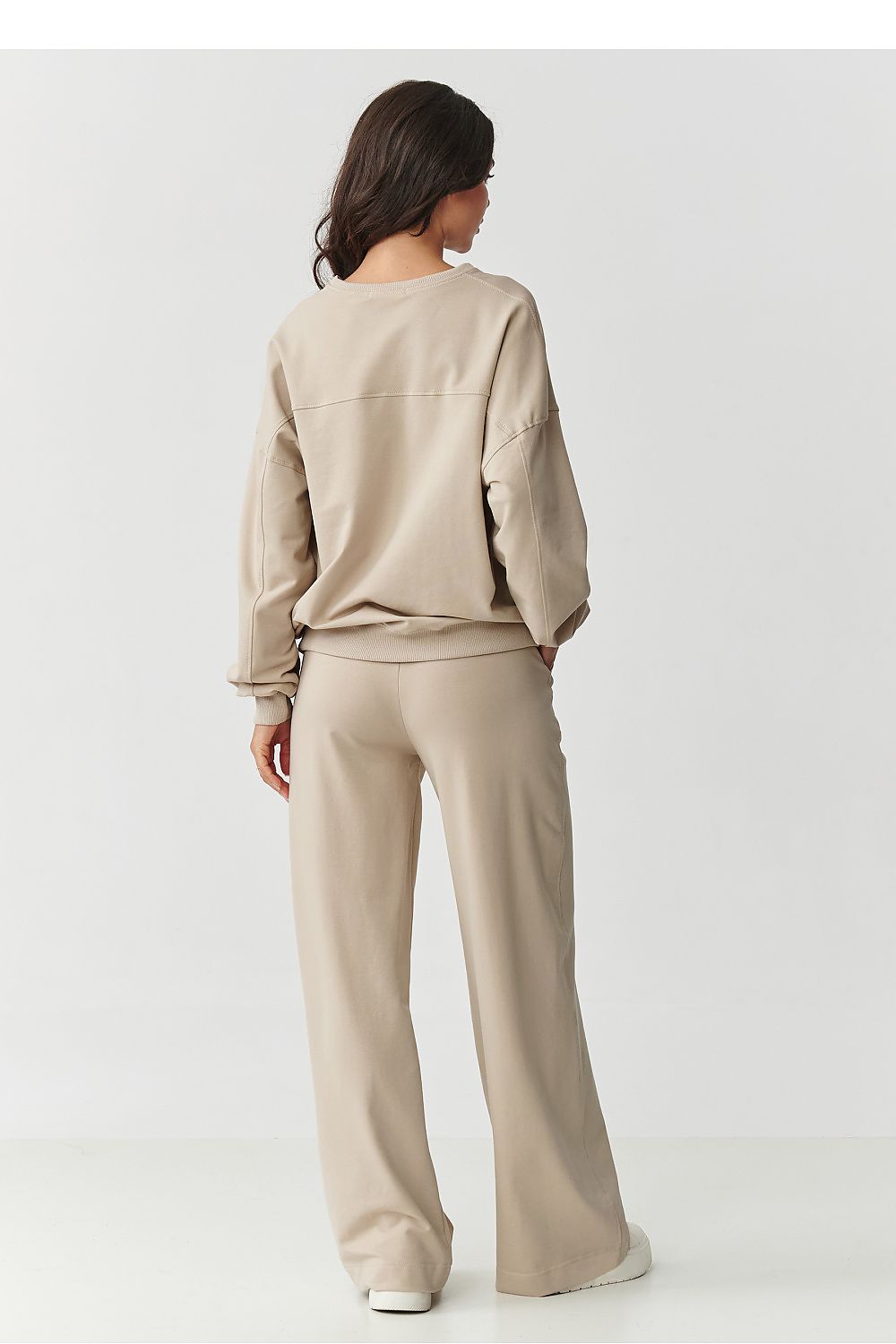 Stylish woman wearing Makadamia women's tracksuit set, demonstrating the relaxed fit of the oversized sweatshirt and trendy wide-legged pants, embodying comfort and chic style.