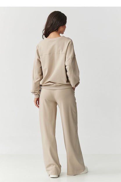 Stylish woman wearing Makadamia women's tracksuit set, demonstrating the relaxed fit of the oversized sweatshirt and trendy wide-legged pants, embodying comfort and chic style.