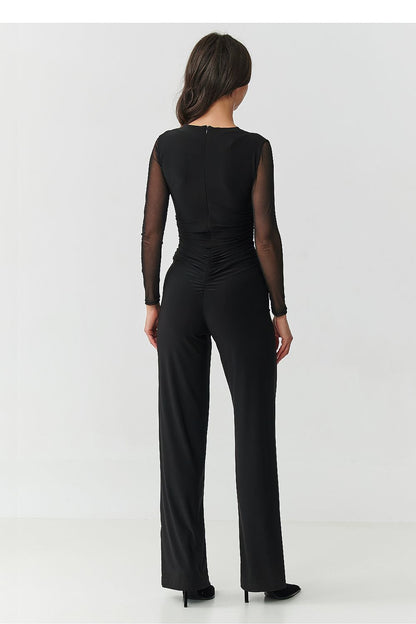 Model wearing the Makadamia elegant black jumpsuit with tulle details, a sophisticated choice for cocktail parties and upscale events.