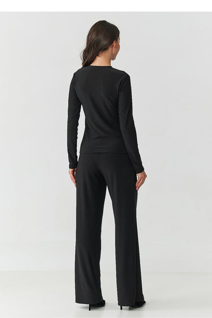 Close-up of elegant black blouse with transparent inserts and high-waisted wide-legged trousers from the Makadamia women's set, showcasing timeless fashion.