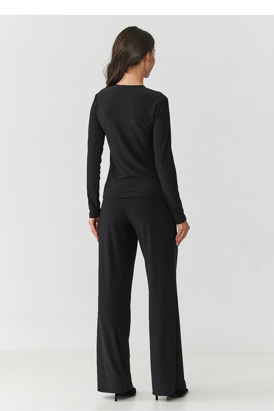 Close-up of elegant black blouse with transparent inserts and high-waisted wide-legged trousers from the Makadamia women's set, showcasing timeless fashion.