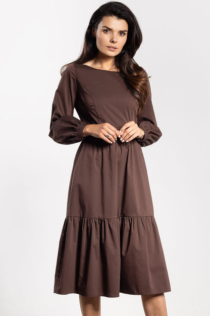 Awama elegant midi dress displayed on a model, demonstrating its graceful flared silhouette and refined long sleeves.