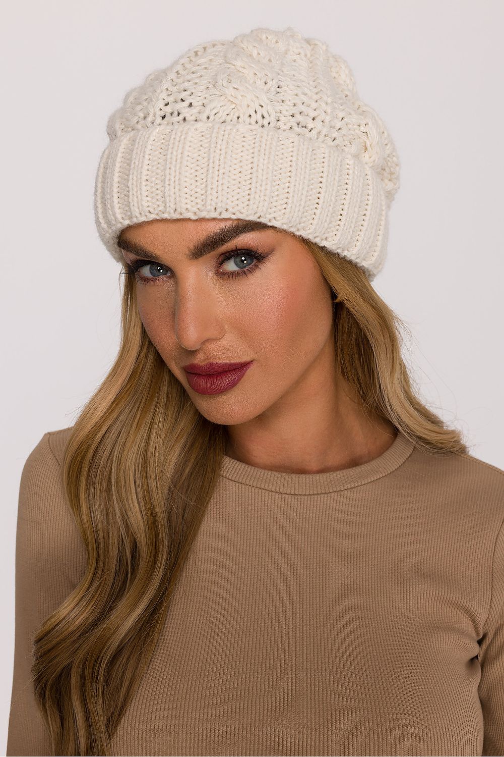 Model wearing the luxury braided knit cap by Moe in a cozy outdoor setting, demonstrating its warmth and elegant knit design ideal for winter fashion.