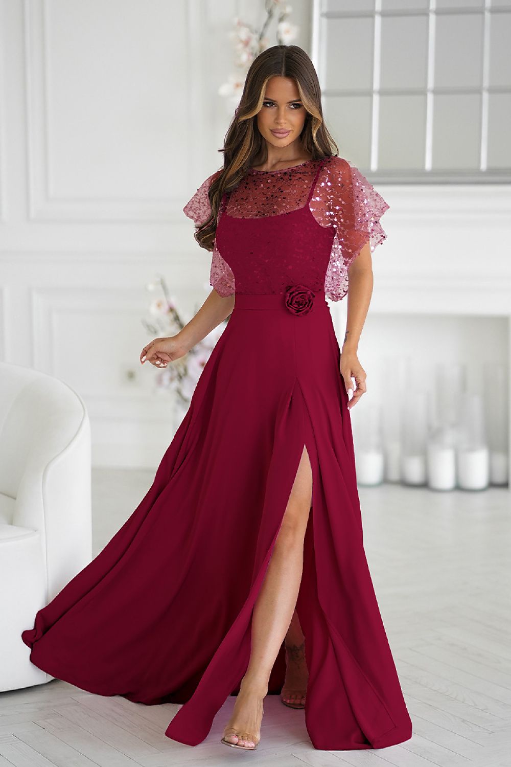 Elegant long dress with a sequined bolero by Bicotone, featuring thin straps and a stylish rose belt, perfect for special occasions and evening outings. Available in sizes EU 38 to 48.