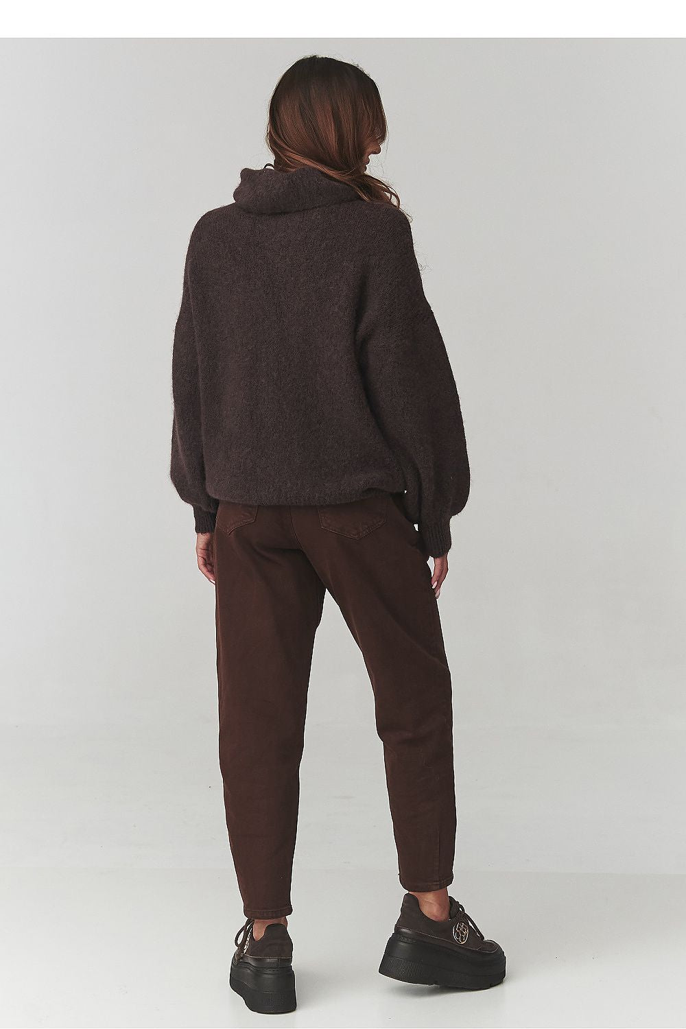 A stylish model wearing the Makadamia oversized turtleneck sweater, presenting an elegant yet casual outfit.