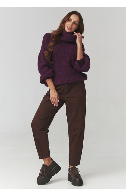 Makadamia women’s knit turtleneck sweater displayed against a backdrop of autumn leaves, emphasising its warming qualities and stylish design.