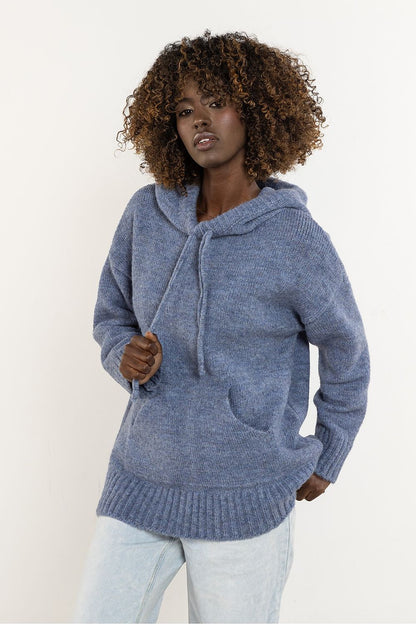Model wearing the Awama wool hooded sweater, captured in a serene outdoor setting, embodying timeless elegance and warmth.