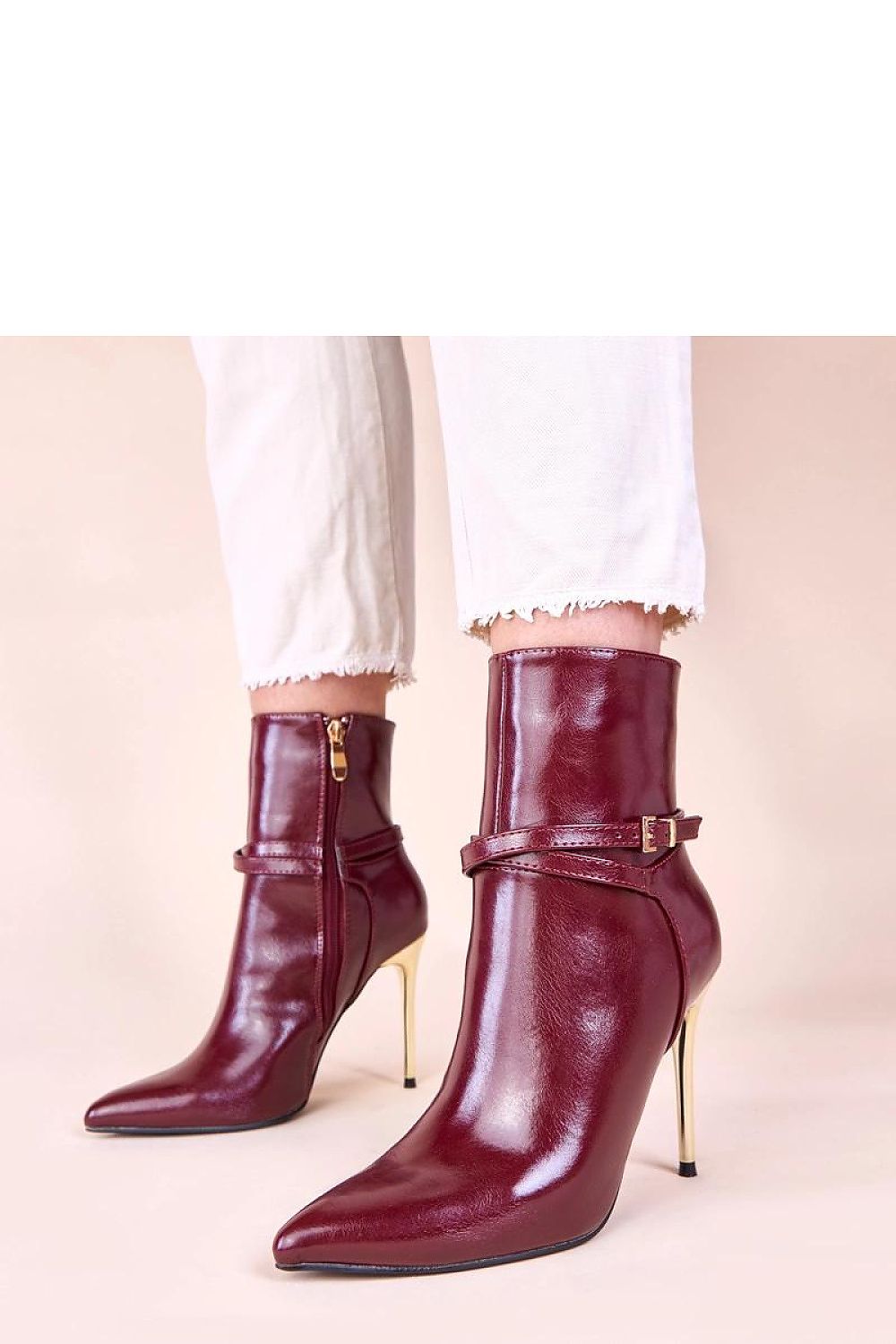 Close-up of exquisite beige ankle boots featuring a radiant gold stiletto heel, ideal for enhancing feminine wardrobe.