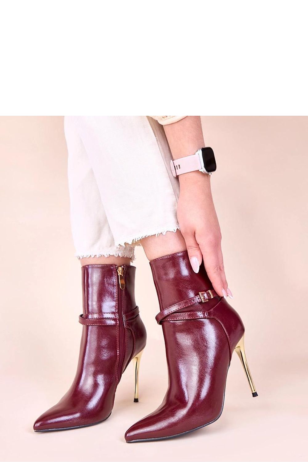 Close-up view of the exquisite gold stiletto accent on beige ankle boots, highlighting the luxurious details and elegant style.