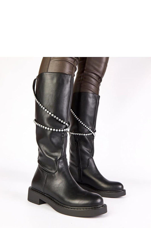 Close-up of Solea's black thigh-high boots featuring a stylish zircon strap, showcasing the exquisite craftsmanship and comfort.