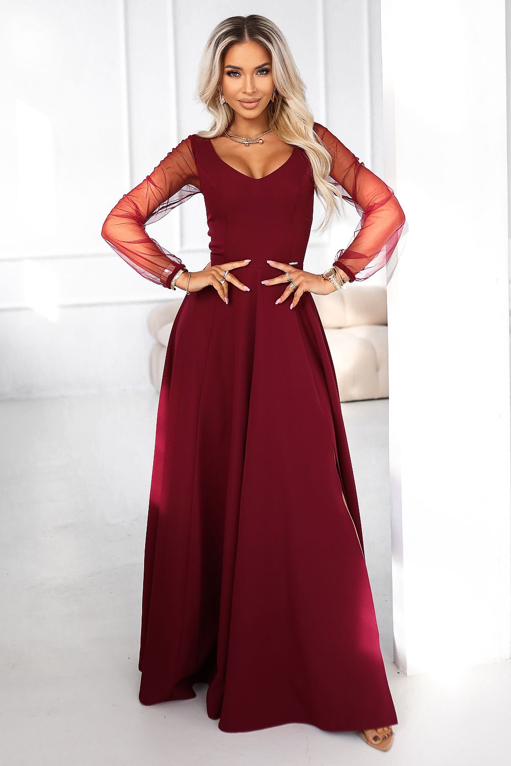 Elegant burgundy maxi dress with tulle sleeves by Numoco, showcasing a flattering fit and sophisticated design in a luxurious setting.