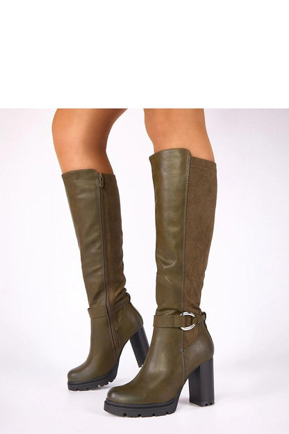 Stylish Zulma green block heel boots from Solea showcased on a post, highlighting their unique buckle detail and sophisticated design ideal for both casual and formal occasions.