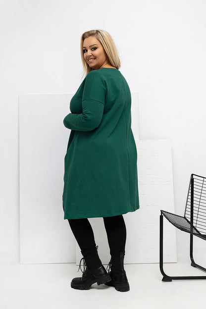 Model wearing the Relevance Plus Size Asymmetrical Tunic Dress with pockets, highlighting its fashionable long sleeves and trendy patch detail for a chic casual look.