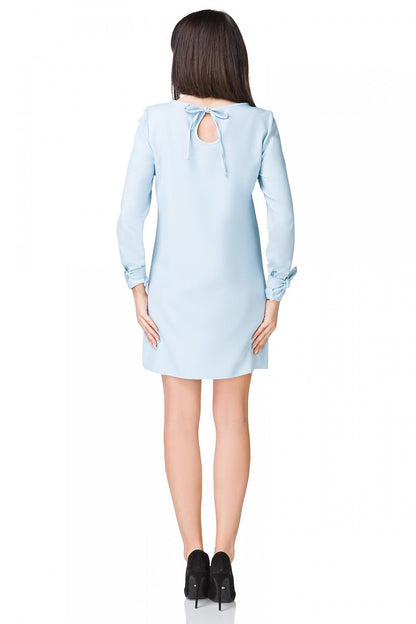 Model wearing the Elegant Mini Dress Tessita styled for a garden party, featuring long sleeves and a flattering trapeze cut.