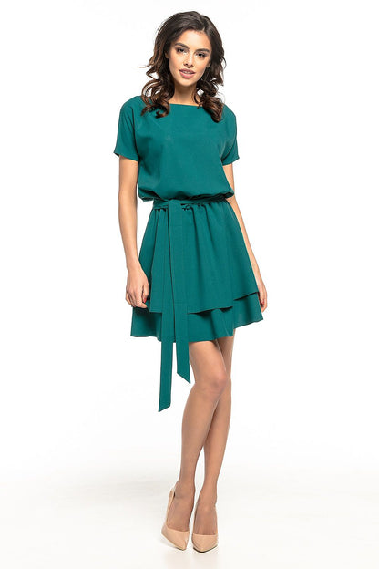 Tessita Daydress styled with a waist tie, highlighting its flattering silhouette and flared double skirt, ideal for formal events.