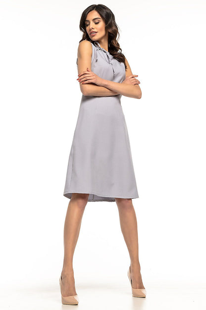 Elegant Tessita Daydress showcased, featuring a trapezoidal hem and decorative tie neckline, perfect for both professional and casual styling. Ideal for ladies who value sophistication.