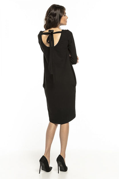 Back view of a chic loose-fitting black tuba dress featuring a stylish tie detail at the neckline, designed by Tessita, perfect for modern elegance.