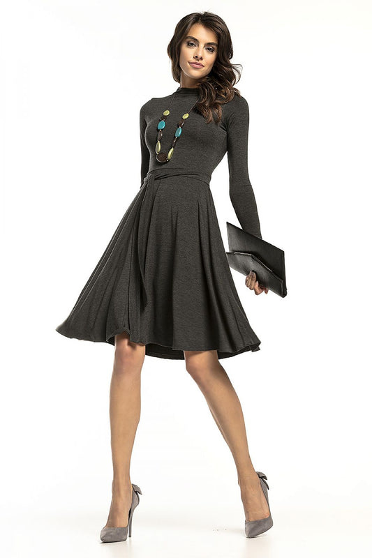 Elegant Tessita long-sleeved turtleneck dress in airy viscose knit, featuring a fitted top and flared bottom, model posed with a clutch for a luxurious look.
