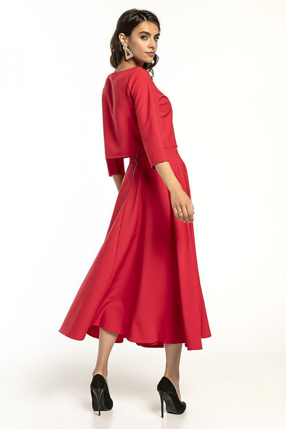 Back view of a stunning red Tessita waist-length blouse featuring 3/4 sleeves, elegantly paired with a flowing skirt, ideal for upscale occasions.