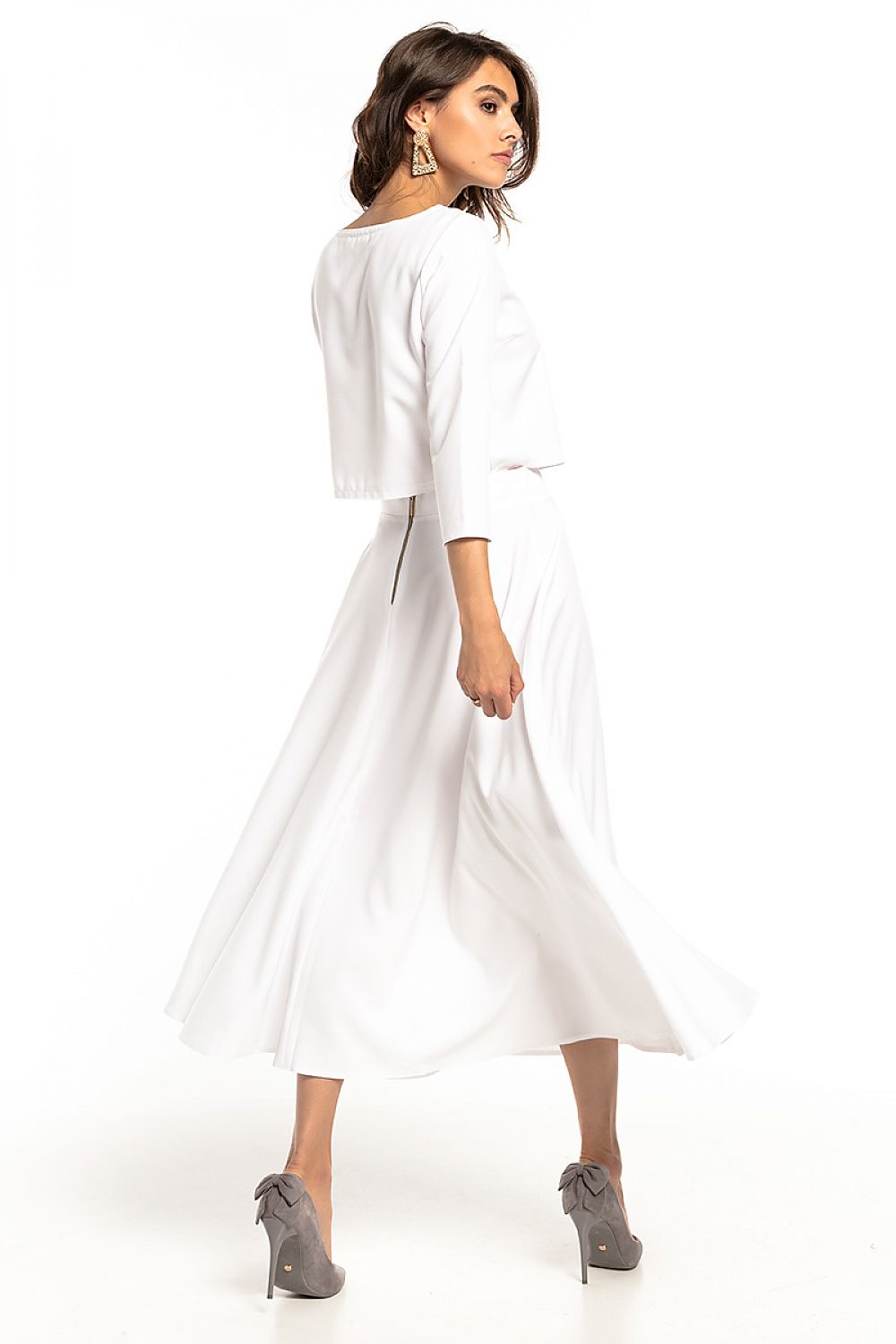 Back view of an elegant Tessita waist-length blouse with 3/4 sleeves, perfectly paired with a flowing white skirt, showcasing timeless style and grace.