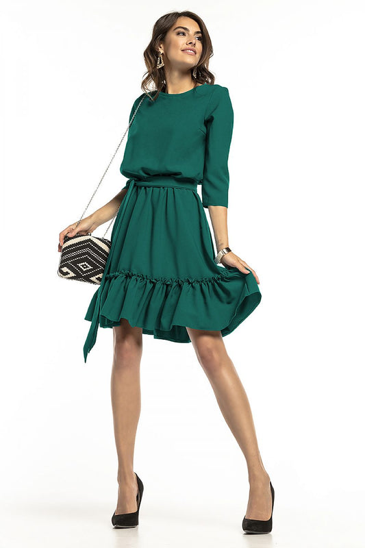 Stylish model showcasing the elegant 3/4 sleeve daydress by Tessita, featuring a flared skirt with decorative frill and a tied belt, perfect for versatile day-to-night looks.