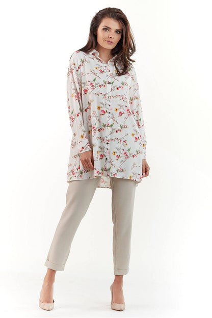 Elegant Long Sleeve Shirt with Charming Crease. A model confidently poses in a stunning floral patterned shirt, accentuated by soft pastel colours, complementing tailored trousers and elegant heels.