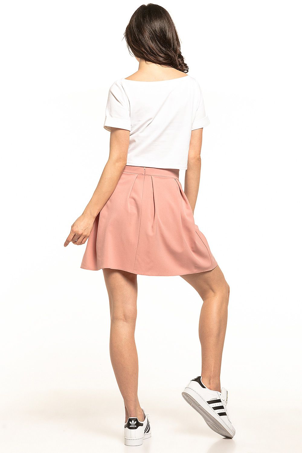 Elegant Tessita women's mini pleated skirt in soft pink, styled for a casual summer look, featuring a concealed zip at the back.