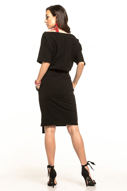 Back view of a stylish black midi dress by Tessita, showcasing kimono sleeves and a pencil cut, complemented by chic accessories and elegant black heels.