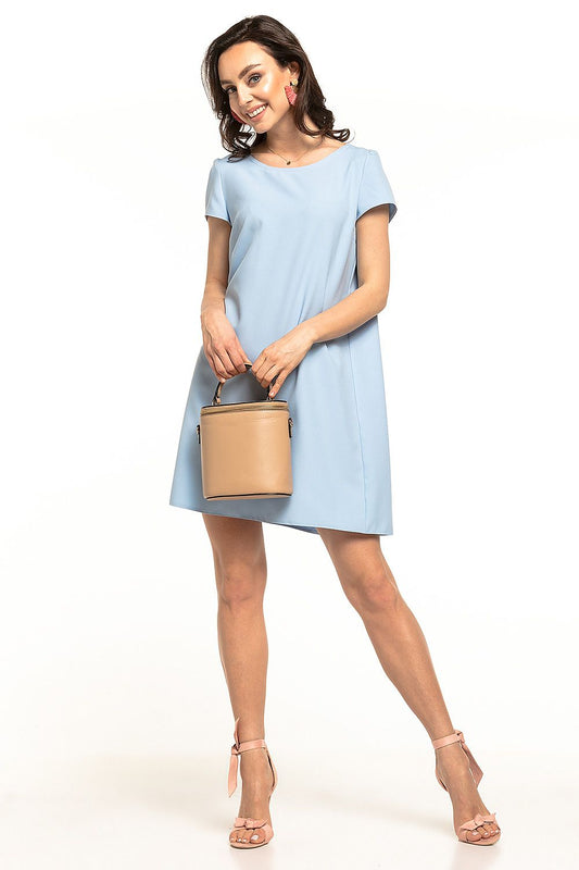 Elegant Tessita mini dress in soft blue featuring a boat neckline and short sleeves, styled with a chic tan handbag and strappy pink heels for a luxurious look.