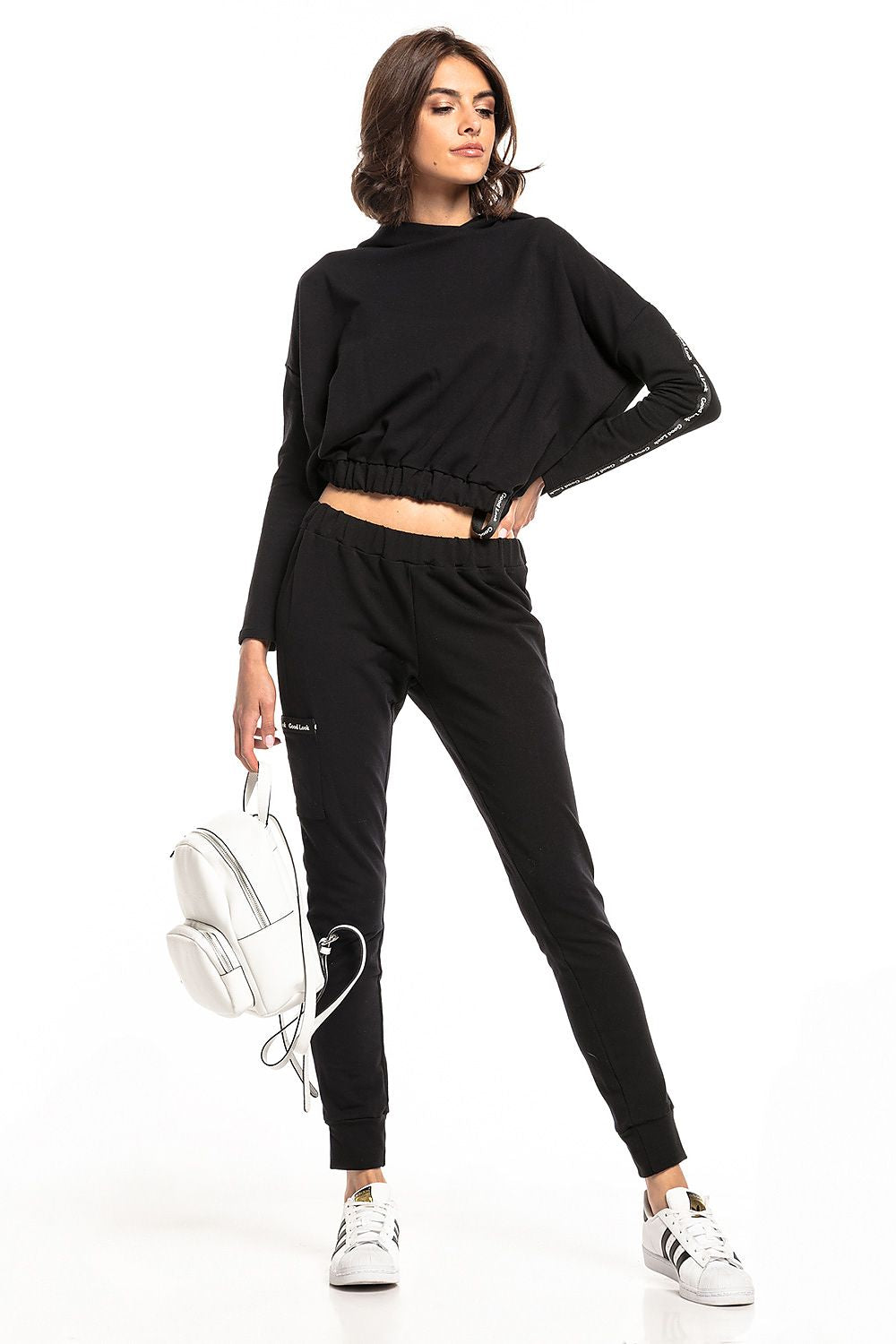 Stylish woman wearing luxury black Tessita straight-cut tracksuit trousers with drawstring waist and matching cropped top, showcasing a chic sporty look.