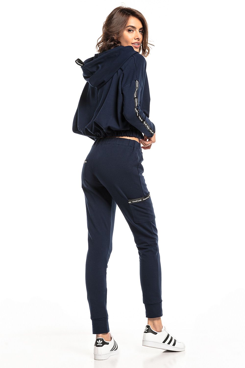 Back view of a stylish model wearing a navy blue Tessita tracksuit with a cropped hooded top and straight-cut trousers, epitomising modern luxury fashion.