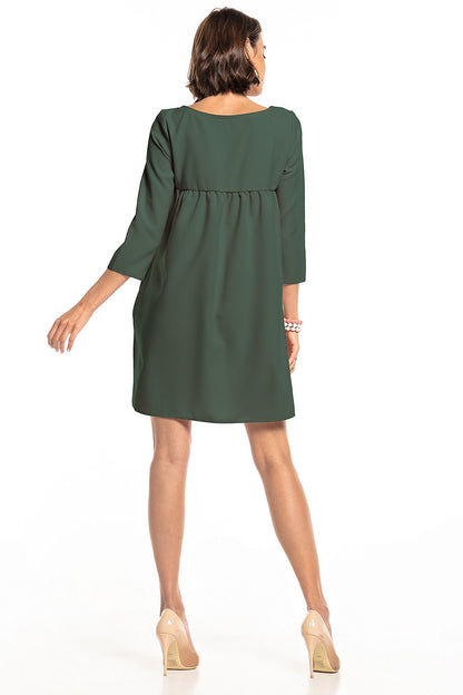 Rear view of the elegant green pleated daydress with pockets by Tessita, highlighting its stylish design and comfortable fit, perfect for a chic daytime look.
