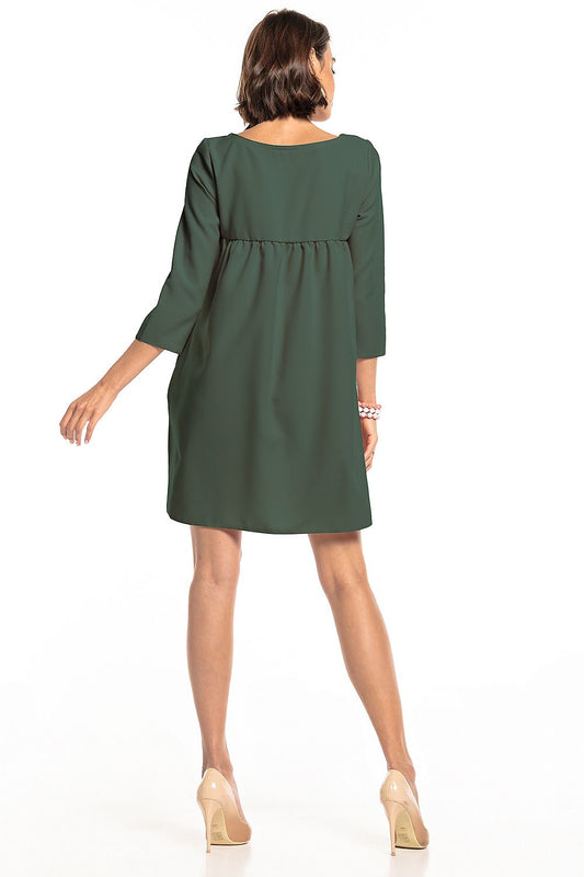 Rear view of the elegant green pleated daydress with pockets by Tessita, highlighting its stylish design and comfortable fit, perfect for a chic daytime look.