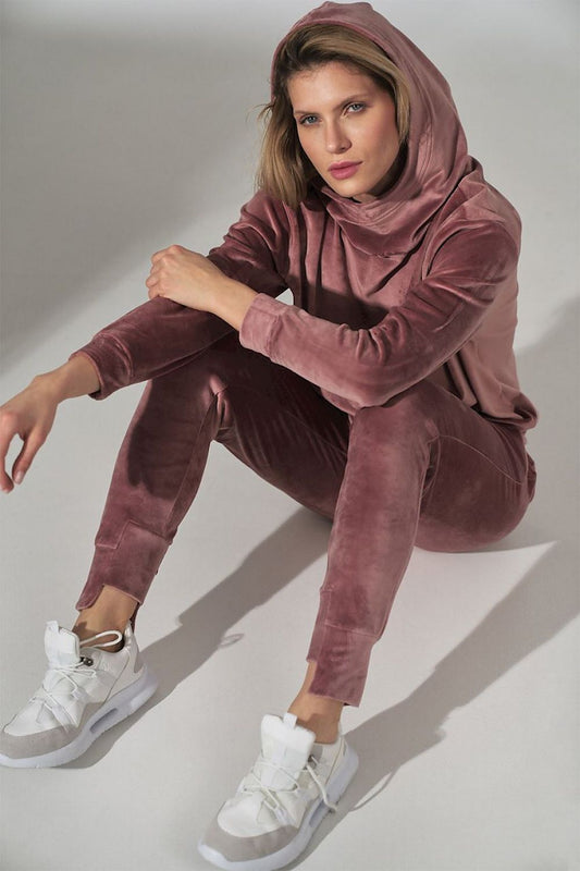 Luxurious Figl Pink Velour Tracksuit Trousers displayed by a model, featuring tapered legs and a drawstring waist, styled with contemporary white sneakers for an elegant yet casual look.