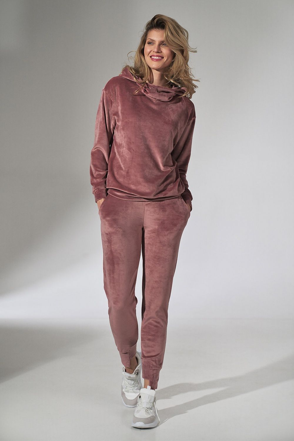 Woman smiling in a Figl Pink Velour Tracksuit Trousers with Tapered Legs and Drawstring Waist, highlighting the luxurious pink hue and casual elegance.