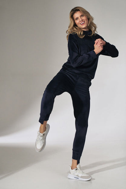 Fashionable Figl Pink Velour Tracksuit Trousers with Tapered Legs and Drawstring Waist, captured in a joyful pose, embodying comfort and chic design.