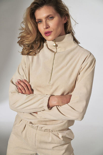 Fashionable woman in a luxurious beige corduroy top, featuring a decorative zipper from Figl's long sleeve collection, embodying modern elegance.