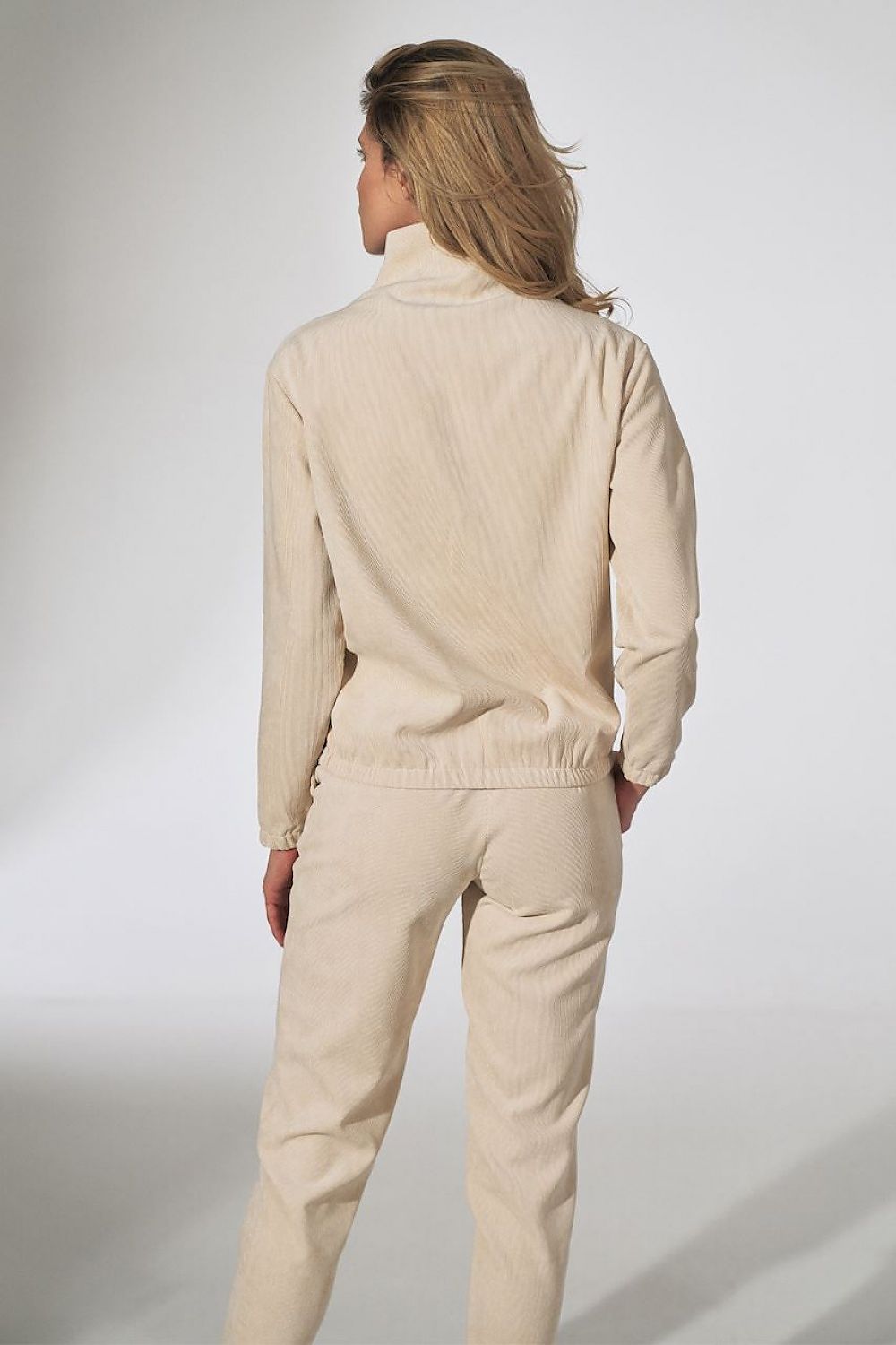 Graceful woman featuring the back view of a trendy beige corduroy top by Figl, designed with a decorative zipper, perfect for elevating any casual outfit.