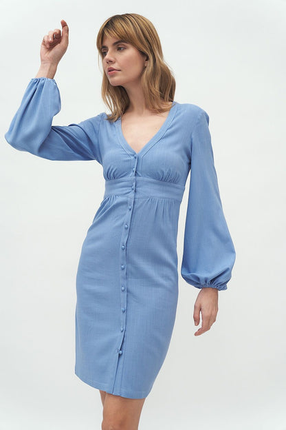 A model showcasing the Elegant Nife Daydress with puffed sleeves, featuring a waist-emphasizing cut, perfect for business attire, in a soft blue hue. Ideal for sophisticated elegance.